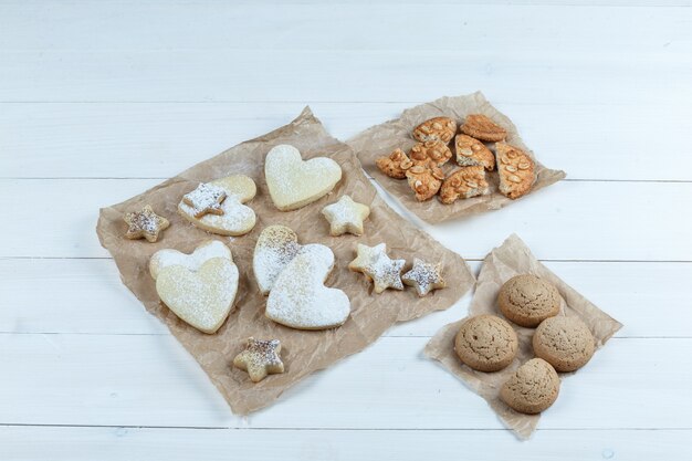 Différents types de cookies sur un morceau de sacs sur un fond de planche de bois blanc. pose à plat.