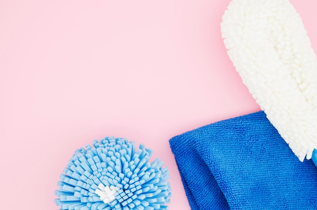 Différents types d&#39;éponges de nettoyage avec une serviette bleue sur fond rose