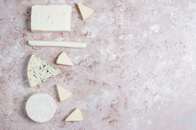 Photo gratuite différents types de fromage sur une surface brun clair