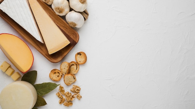 Différents Types De Fromage Avec Une Tranche De Pain; Noyer; Ail Et Feuilles De Laurier Sur Fond Blanc