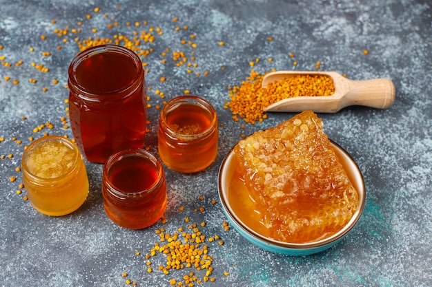 Différents types de miel dans des bocaux en verre, nid d'abeille et pollen