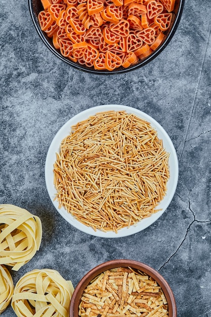 Photo gratuite différents types de pâtes sèches sur la table en marbre.