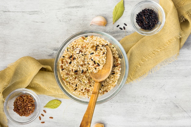 Photo gratuite différents types de riz dans des bols avec une cuillère sur la table