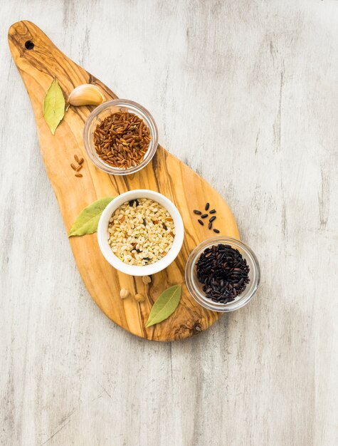 Différents types de riz dans de petits bols sur une planche de bois