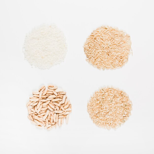 Différents types de riz non cuit en forme circulaire sur fond blanc