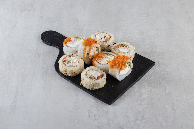 Différents types de rouleaux de sushi placés sur une planche de bois.