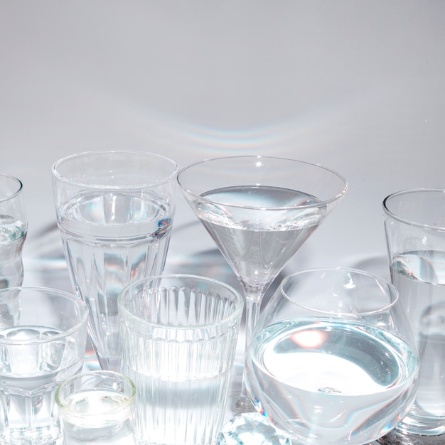 Différents types de verres avec un liquide sur fond gris