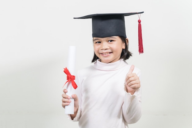 Diplômé de l'école asiatique heureux mignon avec un chapeau de graduation et un diplôme isolé sur fond blanc