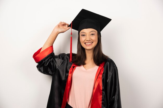 Diplômé frais en robe posant sur fond blanc.