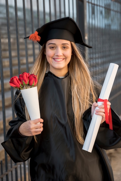 Photo gratuite diplômé vue de face avec bouquet de roses