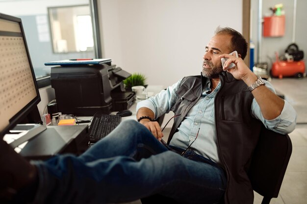 Directeur d'atelier de réparation automobile parlant au téléphone portable au bureau