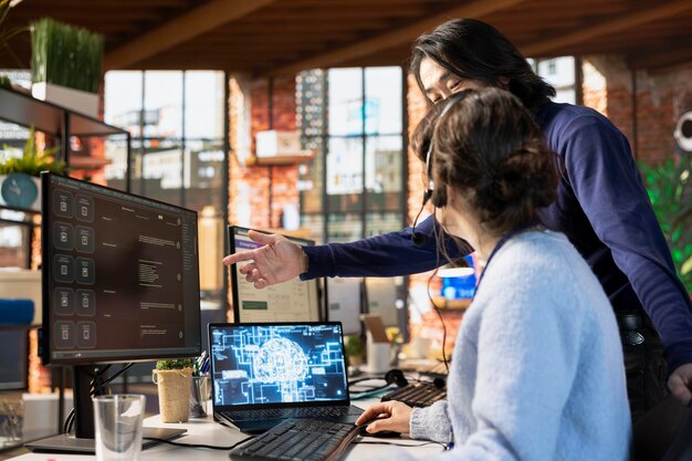 Le directeur du centre d'appels guide le stagiaire sur l'utilisation du chatbot d'IA sur le bureau du bureau sur PC