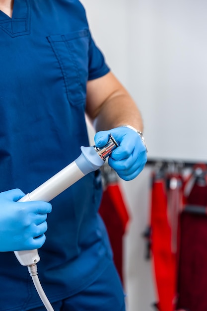 Photo gratuite dispositif de thérapie par ondes de choc avec des mains de médecin dans des gants en caoutchouc