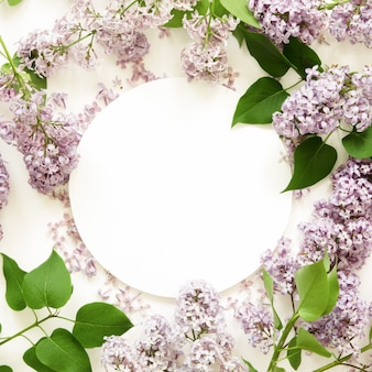 Disposition créative de fleurs lilas avec du papier blanc. maquette. vue d'en-haut.