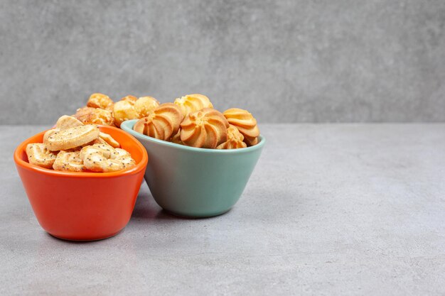 Disposition de divers biscuits et biscuits dans des bols colorés sur fond de marbre.