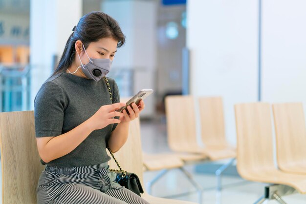 Distanciation sociale avec une femme asiatique portant un masque facial protection contre les virus en attente assis dans une chaise avec une distance d'espace pour prévenir la propagation du virus