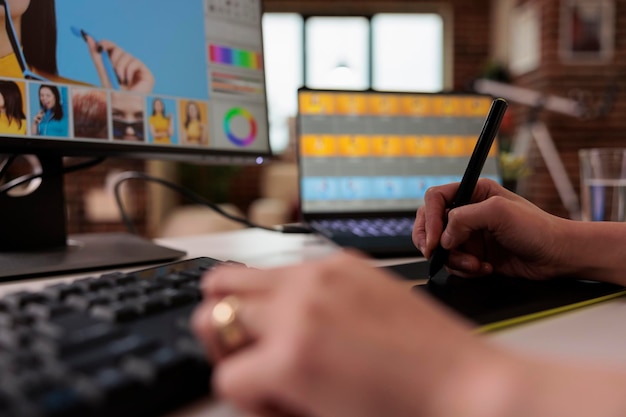 Éditeur féminin utilisant un stylet sur une tablette graphique pour retoucher des photos, créant du contenu photographique professionnel pour la production. Image d'édition indépendante avec un logiciel de retouche créative. Fermer.