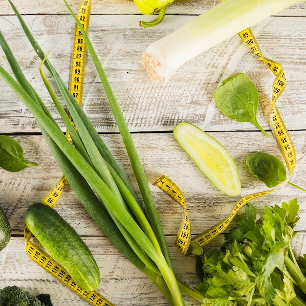 Divers aliments sains verts avec du ruban à mesurer sur une planche de bois