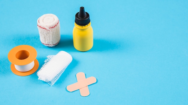 Divers bandages avec une bouteille jaune sur fond bleu