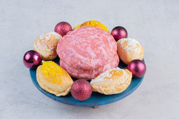 Divers biscuits faits maison et boules de Noël sur tableau bleu.