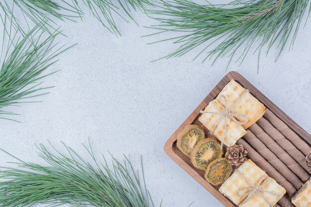 Divers biscuits et tranches de kiwi séchées sur planche de bois.