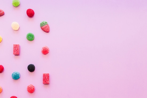 Divers bonbons colorés de gelée de sucre sur fond d'écran rose