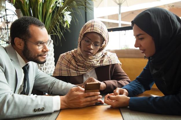 Divers collègues enthousiastes regardant du contenu sur un smartphone