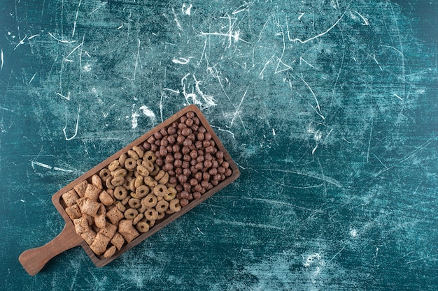 Divers cornflakes sur une planche , sur fond bleu. photo de haute qualité