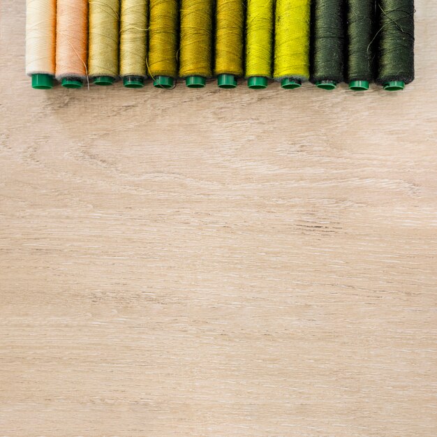 Divers fils colorés disposés en rang sur fond en bois