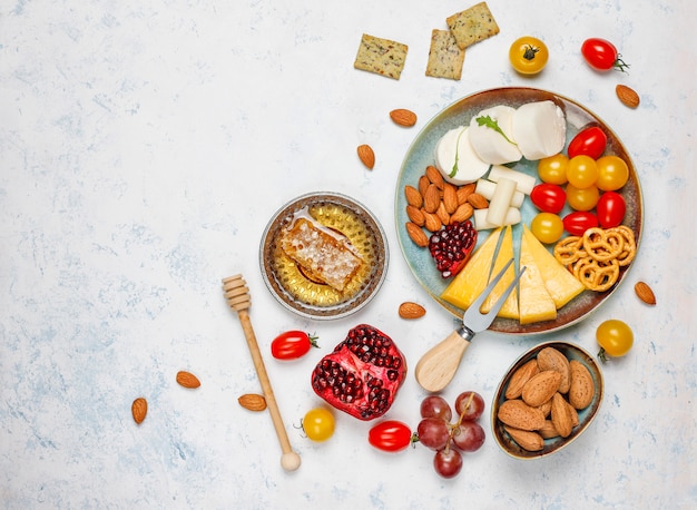 Divers fromages et assiette de fromages sur table lumineuse avec différents fruits à coque et fruits