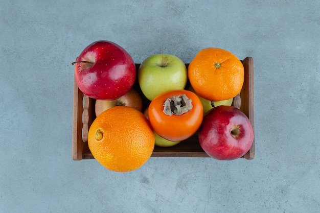 Divers fruits dans une boîte , sur le fond de marbre.