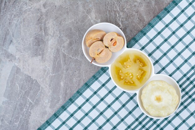 Photo gratuite divers légumes et fruits marinés dans des bols avec nappe.