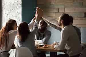 Photo gratuite divers meilleurs amis enthousiastes donnant leur high-cinq ensemble à une réunion au café