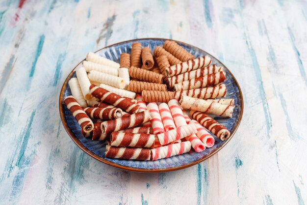 Divers rouleaux de gaufres dans des assiettes en céramique, vue du dessus.