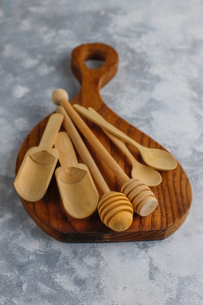 Diverses cuillères en bois avec planche à découper en bois fait main sur béton gris