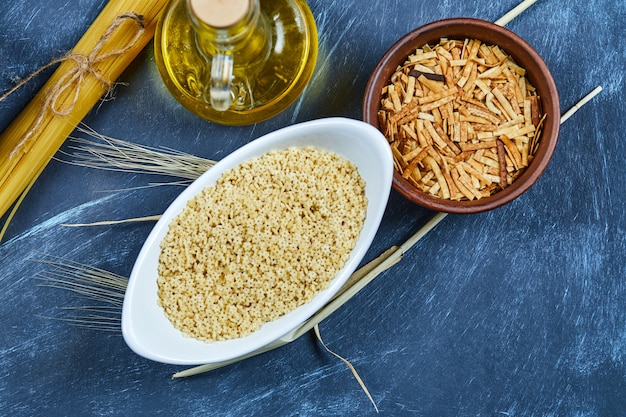 Photo gratuite diverses pâtes non cuites avec une bouteille d'huile, de farine et d'ail.