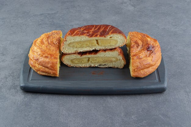 Diverses pâtisseries à moitié coupées sur une planche sombre.