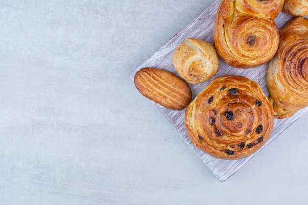 Diverses pâtisseries et petits pains avec des biscuits sur planche de bois.