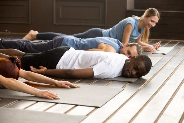 Diverses personnes fatiguées se détendant sur des tapis après une séance de yoga sur des étirements