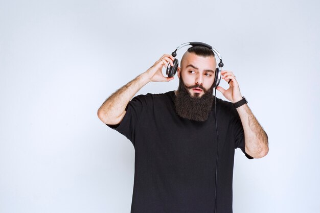 DJ avec barbe portant ou enlevant les écouteurs.