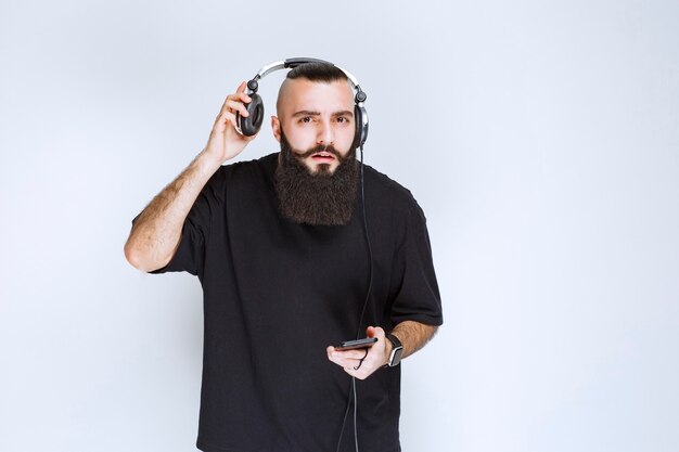 Dj avec barbe sortant des écouteurs pour écouter la voix extérieure.