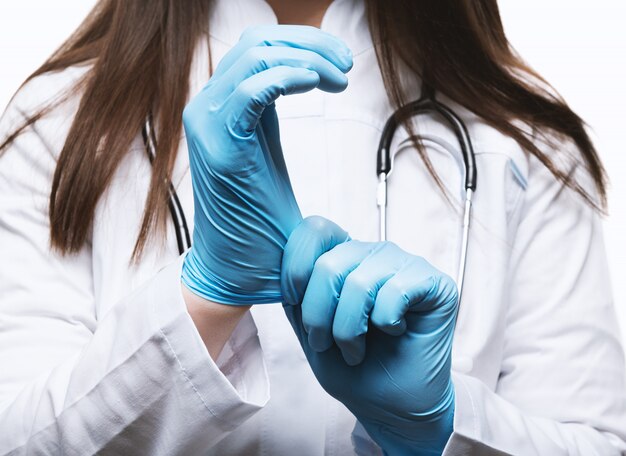 Docteur en blouse blanche avec stéthoscope, portant des gants.