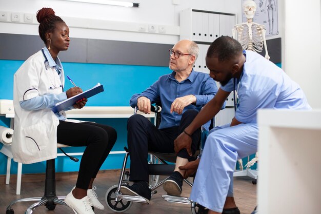 Docteur et infirmière aidant l'utilisateur d'un fauteuil roulant
