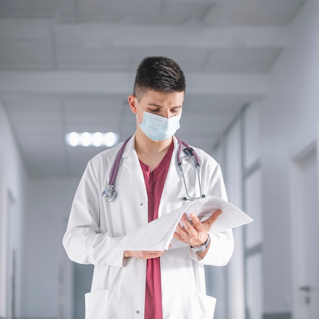 Photo gratuite docteur en masque avec des papiers