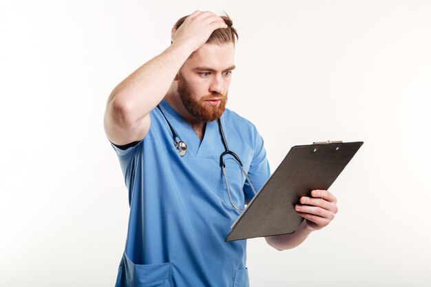 Docteur en médecine pensif ou infirmière avec stéthoscope regardant presse-papiers