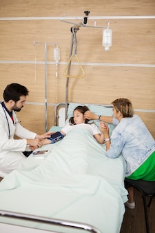 Docteur prenant la tension artérielle de son patient dans la chambre d'hôpital