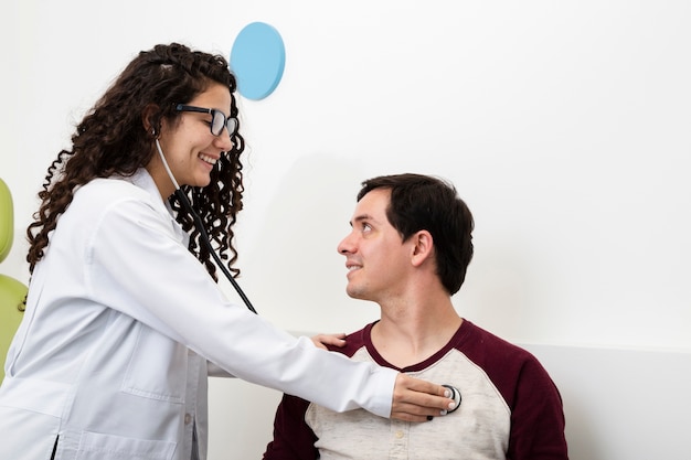 Docteur smiley vue de côté vérifiant un patient