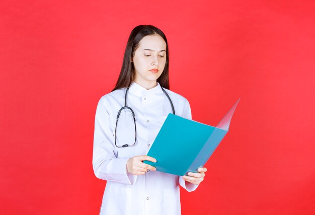 Docteur avec un stéthoscope tenant l'histoire du patient et la vérifiant.