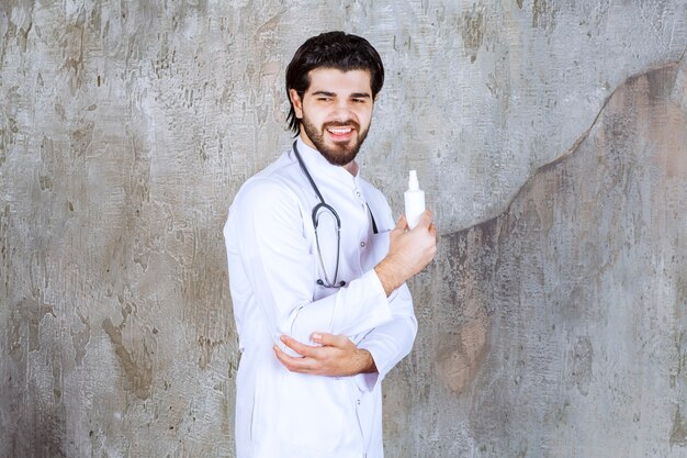 Docteur avec un stéthoscope tenant un tube blanc de spray désinfectant pour les mains