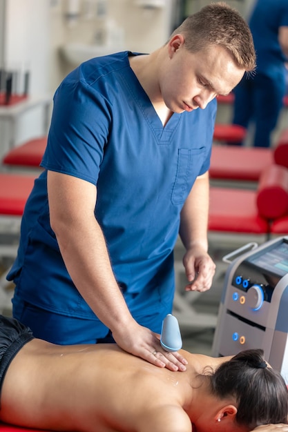 Photo gratuite docteur utilisant une machine pour traiter le dos d'un patient